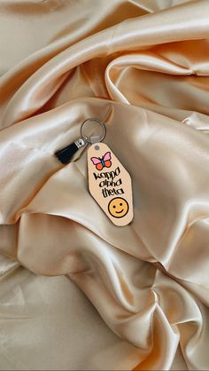 a keychain with a smile on it sitting on top of a satin fabric