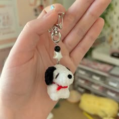 a hand holding a small keychain with a dog on it