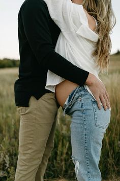 a man and woman are kissing in a field with tall grass on the other side