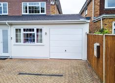 a house with a white garage door and brick driveway