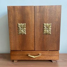 a wooden cabinet with two brass handles on it