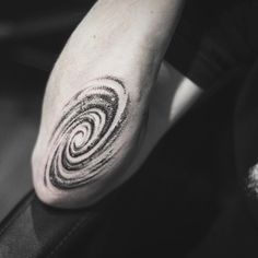 a black and white photo of a person's foot with a spiral tattoo on it