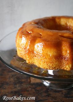 a bundt cake sitting on top of a glass plate covered in caramel glaze