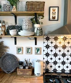 a kitchen with black and white tiles on the wall, shelves above the stove top