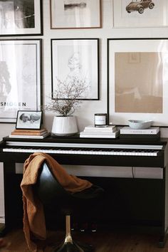 a black piano sitting in front of pictures and a vase with some flowers on it