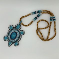 a blue and white beaded necklace on a brown cord with a flower pendant hanging from it