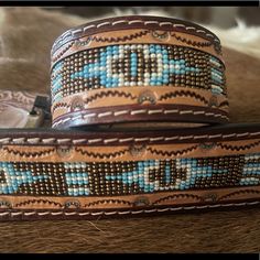 two brown and blue beaded belts sitting on top of a table