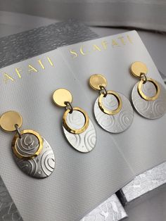 "The round and oval swirled brass drops are plated with a glossy silver alloy which is a mix of different base metals. The pounded looking brass ring is 18k gold plated over brass. The posts are available in either 18 K gold or a silver alloy over pewter. Both the silver and gold are rack plated. This means that the pieces are hand hung so they receive the optimal amount of coverage. We Offer this Earring in Two Different Shapes and Finishes as Follows: 1)Large Round Earrings with Gold Posts - 1 Modern Oval Pendant Earrings For Gift, Gold And Silver Earrings, Navy Earrings, Patina Earrings, Mixed Metal Earrings, Hand Painted Earrings, Oval Earrings, Painted Earrings, Earrings Round