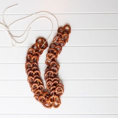 two brown and black necklaces sitting on top of a white table next to a string