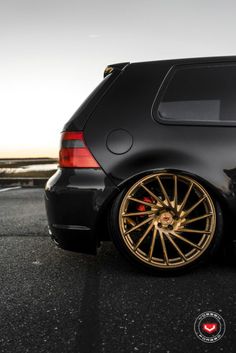 a black car with gold rims parked on the street