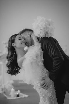 a bride and groom kissing in front of a fountain at their wedding reception, black and white photo