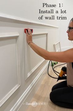 a woman is painting the wall with white paint and she has her hands on it