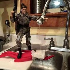 a toy soldier standing on top of a sink next to a kitchen faucet