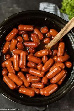 cooked hot dogs in a crock pot with a wooden spoon and parsley on the side