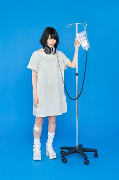 a woman with headphones on standing next to a blue background holding an old fashioned telephone