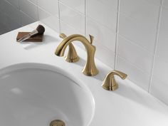 a bathroom sink with gold faucet and soap dispenser