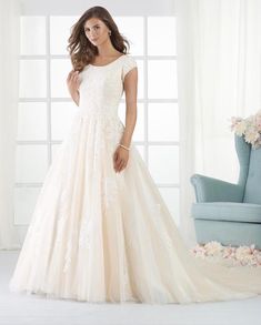 a woman in a wedding dress standing next to a blue chair and flowered wall