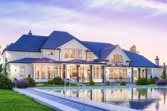 a large white house sitting next to a pool in front of a lush green field