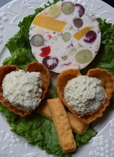 cheese and crackers are arranged on a white plate with lettuce, grapes, and other food items