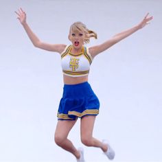 a woman is jumping in the air with her arms out and legs spread wide as she wears a cheerleader outfit