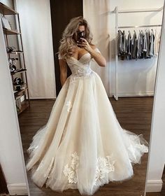 a woman in a wedding dress taking a selfie with her cell phone while standing in front of a mirror