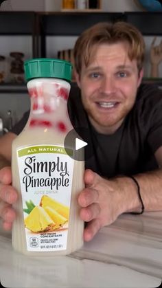 a man holding up a bottle of simply pineapple