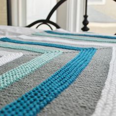 a close up of a bed with a crocheted blanket on top of it