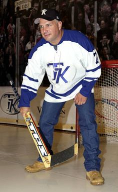 a man holding a hockey stick in front of a goalie net with fans watching