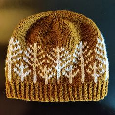 a brown and white knitted hat sitting on top of a wooden table next to a black surface