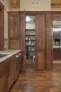 a kitchen with wooden cabinets and stainless steel refrigerator freezer next to an open book shelf