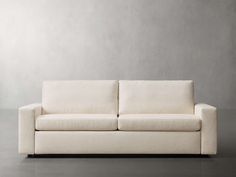 a white couch sitting on top of a floor next to a gray wall in an empty room