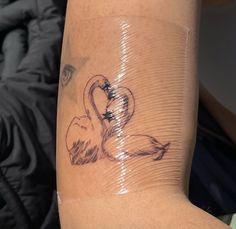 a woman's arm with a tattoo on it that has two swans in the shape of hearts