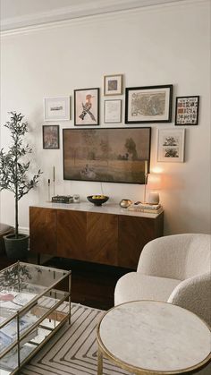 a living room filled with furniture and framed pictures on the wall above a coffee table