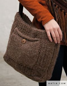 a woman carrying a brown purse with fringes on it's handles and shoulder