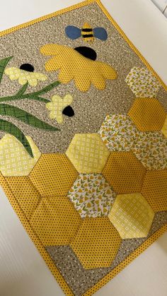 a close up of a patchwork quilt with bees and flowers on the back ground