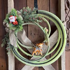 a christmas wreath on top of a wooden fence with a deer figurine in the center