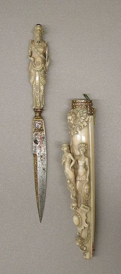 two ivory figurines are next to each other on a gray surface and one is holding a knife