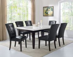 a dining room table with black chairs and a white marble top in front of a window