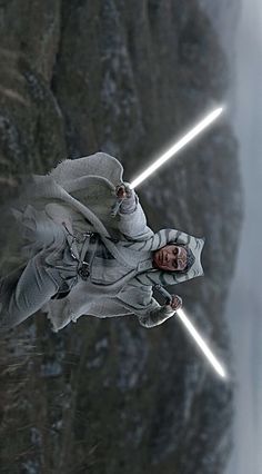 a man with two lightsabens standing in front of a mountain