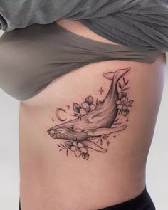 a woman's stomach with a whale tattoo on the side and flowers around it