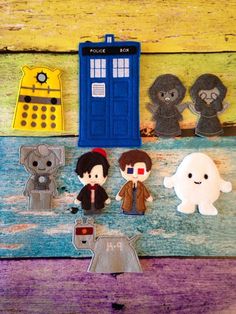 doctor who paper dolls are sitting on a wooden table next to a blue phone booth