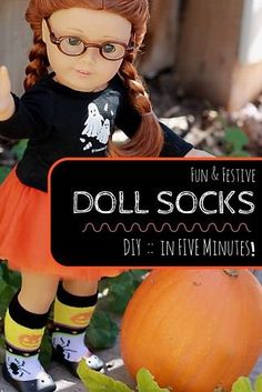 a doll with glasses is standing next to a pumpkin and has her hands up in the air