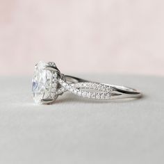 a white gold ring with an oval cut diamond and pave set diamonds on the band