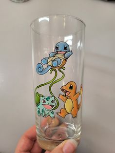 a hand holding a glass with cartoon drawings on it