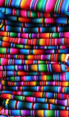 multicolored fabric is stacked on top of each other in the dark, and it looks like they have been made out of yarn