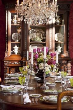 a dining room table is set with place settings and flowers on the centerpieces