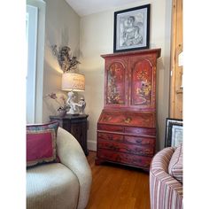 a living room with a chair, dresser and pictures on the wall