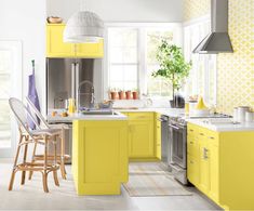 a kitchen with yellow cabinets and white counter tops, an island in the middle is surrounded by chairs