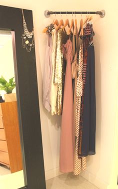 an image of a closet with clothes hanging on the rack and other items in it