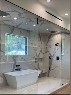 a bathroom with marble walls and flooring in the shower area, along with a white bathtub